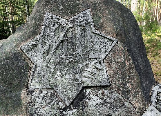 Przestrzeń, która łączy – spacer przez historię i krajobraz Głaz z płaskorzeźbą siedmioramiennej gwiazdy na której widać scenę z życia Św. Huberta.