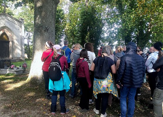 Przestrzeń, która łączy – spacer przez historię i krajobraz Grupa uczestników spaceru na cmentarzu ewangelickim, w tle zabytkowa neogotycka kaplica grobowa..