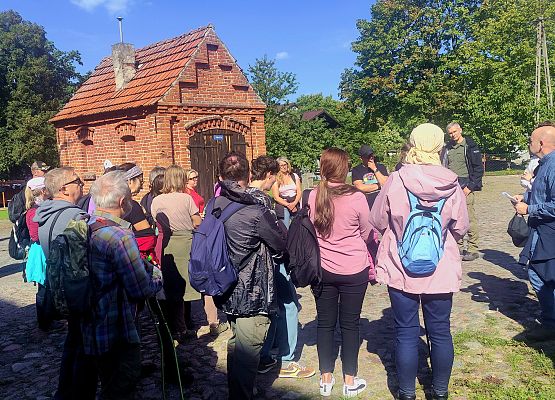 Przestrzeń, która łączy – spacer przez historię i krajobraz Grupa uczestników spaceru w Jarcewie, w tle zabudowania folwarku.