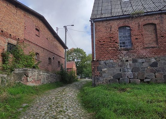Przestrzeń, która łączy – spacer przez historię i krajobraz Fragment zabytkowej zabudowy w Jarcewie wykonane z czerwonej cegły i kamienia.